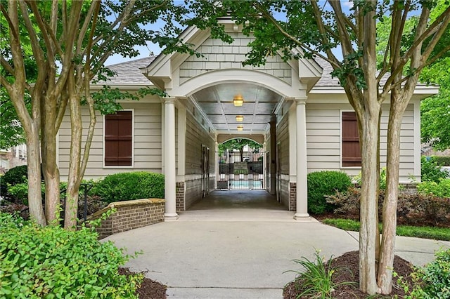doorway to property with roof with shingles and concrete driveway