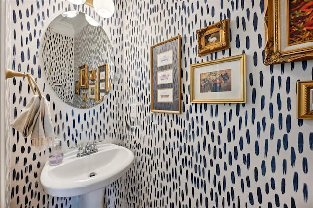 bathroom with crown molding, wallpapered walls, and a sink
