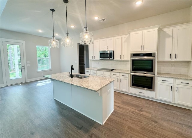 kitchen with appliances with stainless steel finishes, sink, hardwood / wood-style flooring, and backsplash