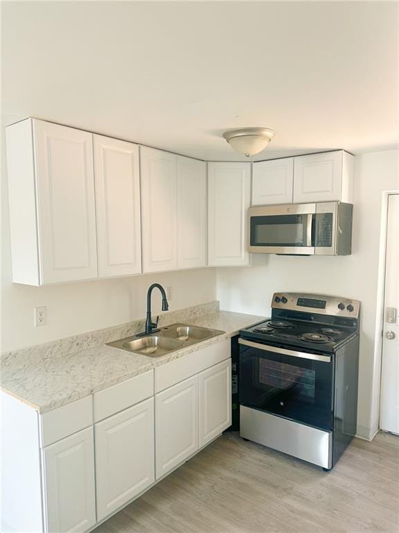 kitchen with stainless steel appliances, light hardwood / wood-style floors, sink, and white cabinets