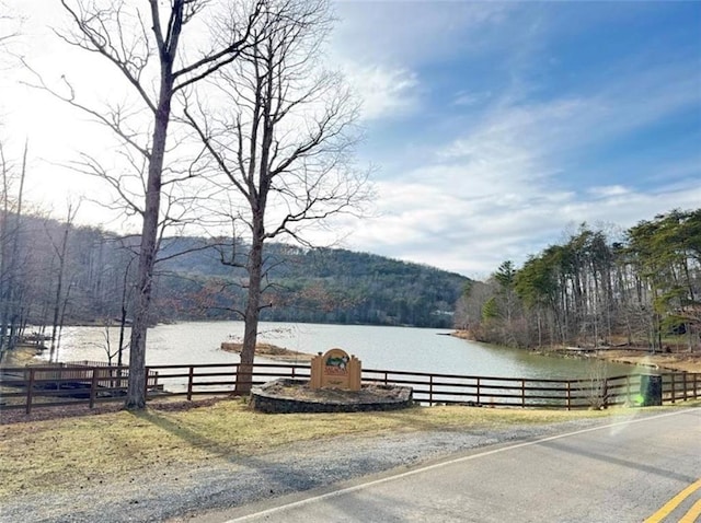 property view of water with fence and a forest view