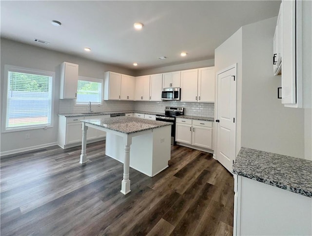 kitchen featuring white cabinets, sink, light stone countertops, a kitchen island, and stainless steel appliances