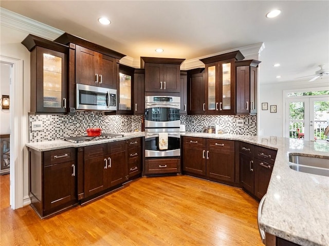 350 Fountain Oaks Ln, Atlanta, GA 30342 - kitchen featuring stainless steel appliances, crown molding, light wood finished floors, dark brown cabinetry, and tasteful backsplash