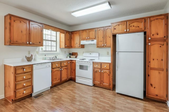 798 Tommy Lee Cook Rd, Palmetto, GA 30268 - kitchen with white appliances, under cabinet range hood, light wood-style flooring, and brown cabinets