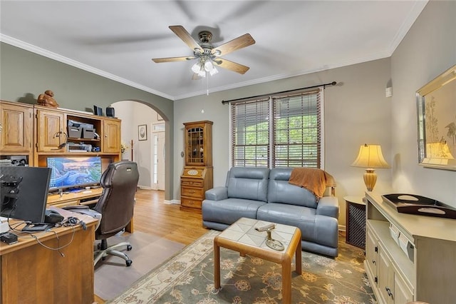 office space featuring crown molding, arched walkways, ceiling fan, and light wood-style flooring