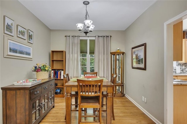 dining space featuring baseboards, light wood finished floors, and a notable chandelier