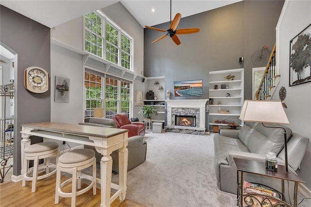 living room featuring a ceiling fan, a fireplace, and high vaulted ceiling