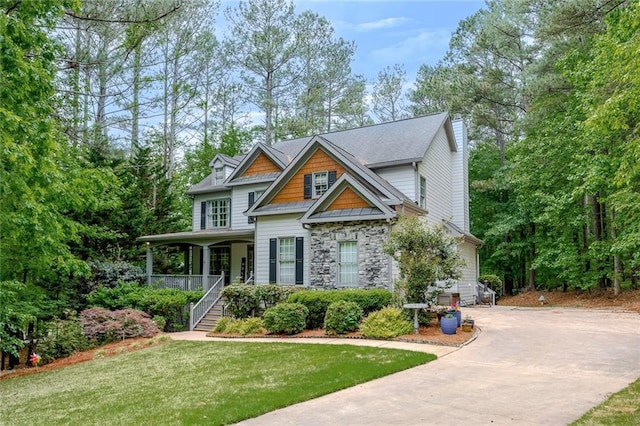 craftsman house featuring a porch, driveway, a front yard, stairs, and stone siding