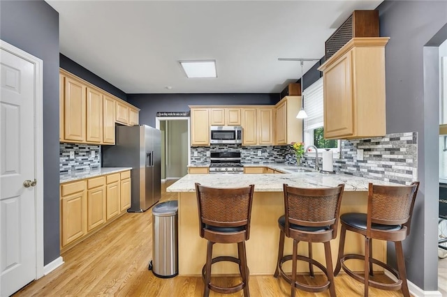 kitchen featuring a sink, light brown cabinets, stainless steel appliances, a peninsula, and decorative backsplash