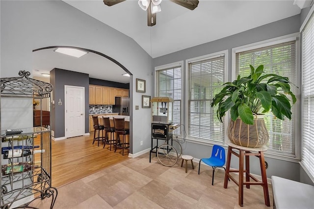 dining space with baseboards, arched walkways, ceiling fan, and a healthy amount of sunlight