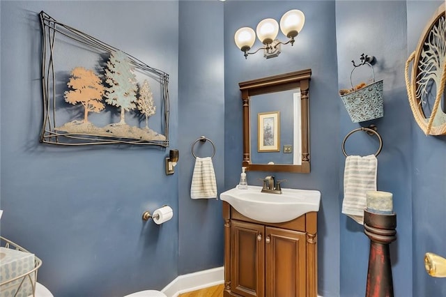 half bath featuring vanity, baseboards, and toilet