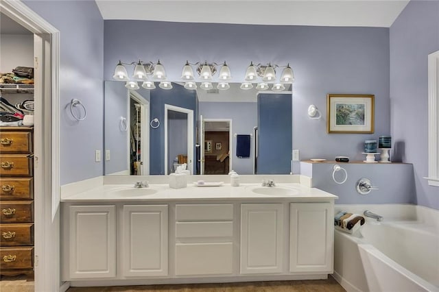 full bathroom featuring double vanity, a walk in closet, a sink, and a bath