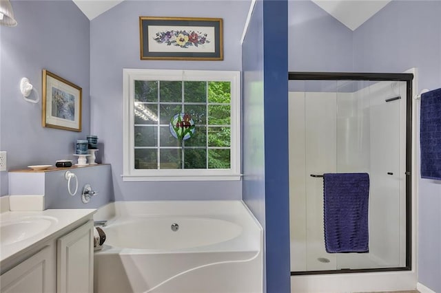 bathroom featuring vanity, a bath, a stall shower, and vaulted ceiling