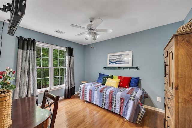 bedroom featuring visible vents, baseboards, ceiling fan, and wood finished floors