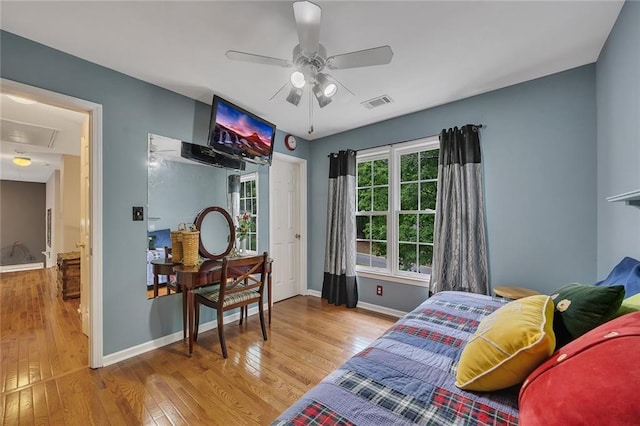 bedroom with visible vents, attic access, baseboards, and wood finished floors