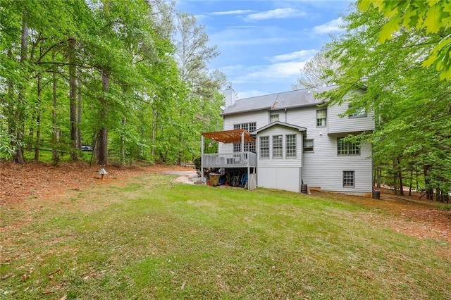 back of property featuring a lawn, a chimney, and a deck