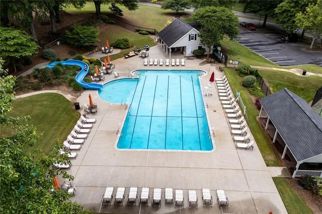 community pool featuring a water slide and a patio area