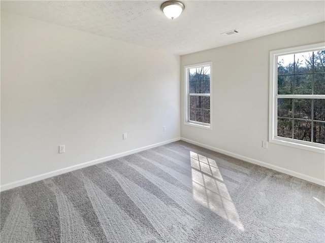 carpeted spare room with visible vents, a textured ceiling, and baseboards