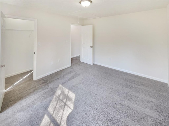 unfurnished bedroom featuring attic access, baseboards, and carpet floors