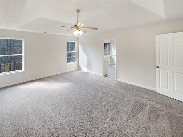 unfurnished room featuring a raised ceiling, baseboards, carpet floors, and a textured ceiling