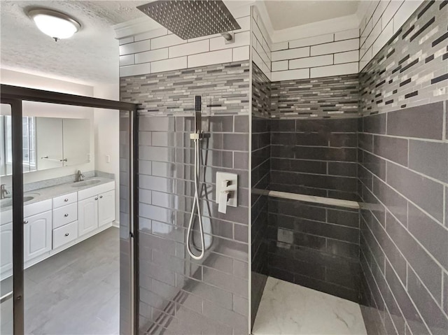 full bath featuring a textured ceiling, double vanity, a walk in shower, and a sink