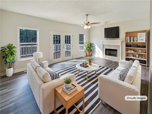 living room featuring wood finished floors, baseboards, a ceiling fan, a fireplace, and french doors