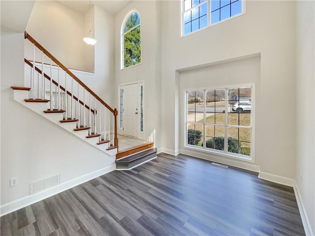 entrance foyer with stairs, wood finished floors, visible vents, and baseboards