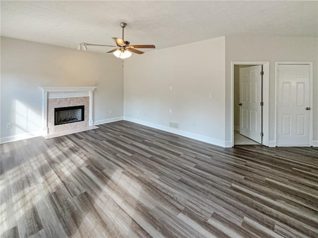 unfurnished living room with visible vents, baseboards, dark wood-style flooring, and a tiled fireplace