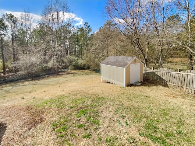 view of yard featuring an outbuilding, fence, and a shed