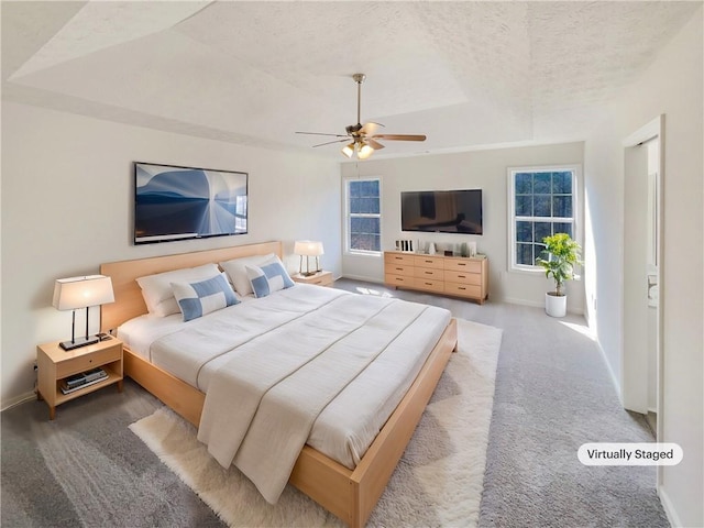 carpeted bedroom with a raised ceiling, multiple windows, baseboards, and a textured ceiling