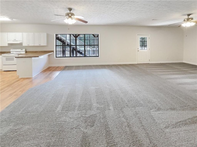 unfurnished living room featuring a textured ceiling, a healthy amount of sunlight, and a ceiling fan