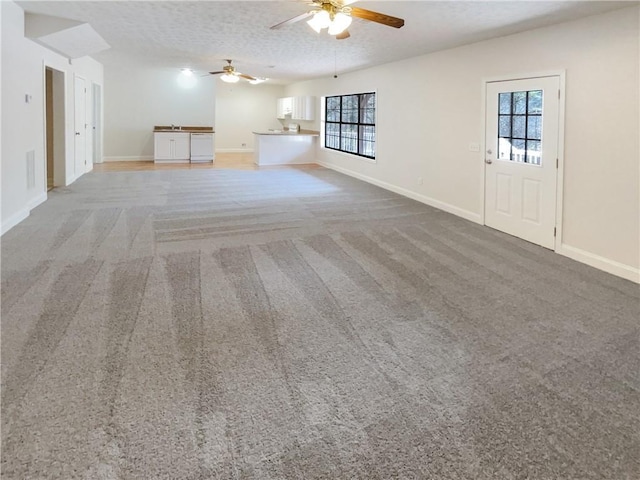 unfurnished living room featuring light colored carpet, a textured ceiling, and a healthy amount of sunlight