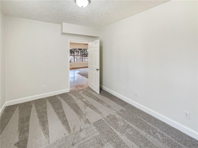 spare room featuring baseboards, carpet, and a textured ceiling