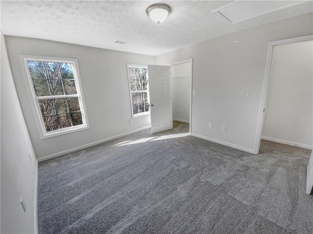 unfurnished bedroom with attic access, multiple windows, and carpet