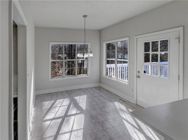 unfurnished dining area with tile patterned flooring, an inviting chandelier, and baseboards