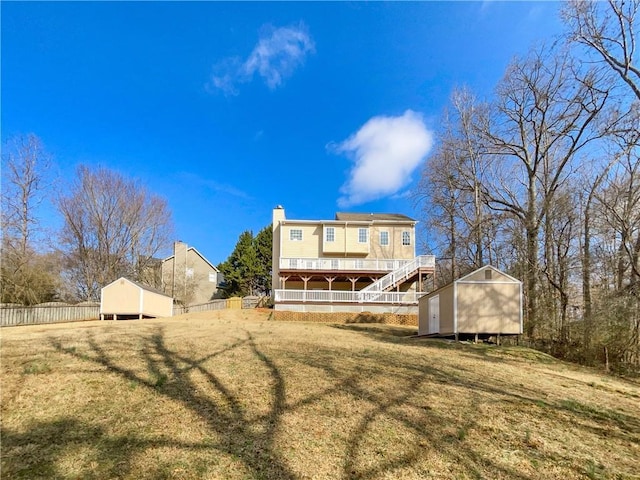 back of property featuring a storage unit, an outdoor structure, stairs, and fence