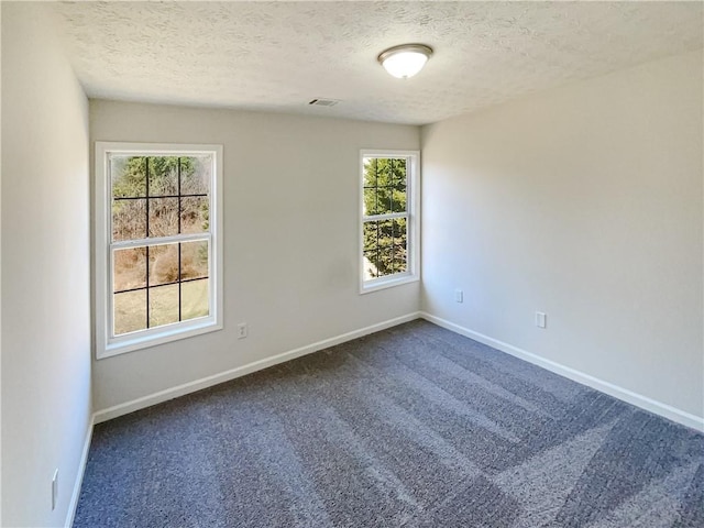 empty room featuring visible vents, baseboards, and dark carpet