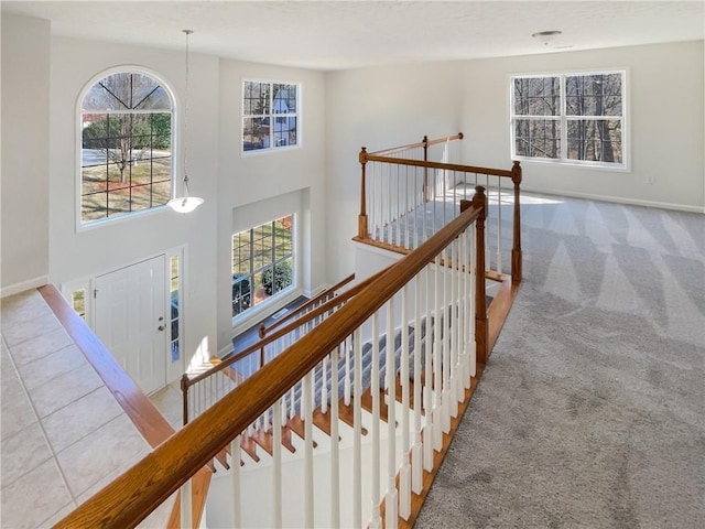 carpeted foyer with tile patterned flooring, baseboards, and a towering ceiling