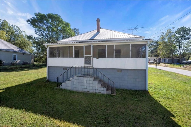 rear view of property featuring a yard and a sunroom