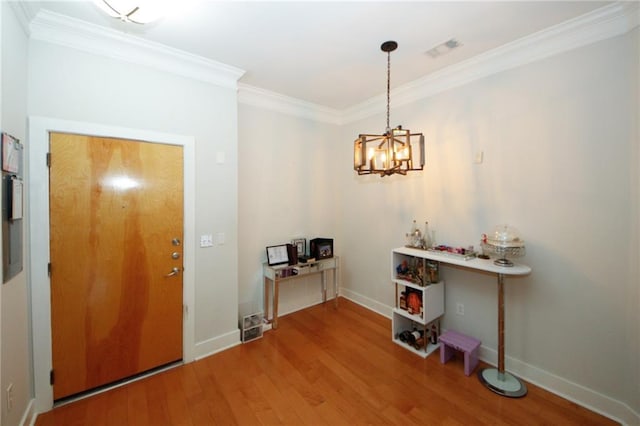 foyer with ornamental molding, wood-type flooring, and an inviting chandelier