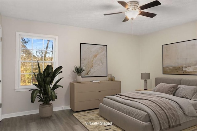 bedroom featuring a ceiling fan, baseboards, and wood finished floors