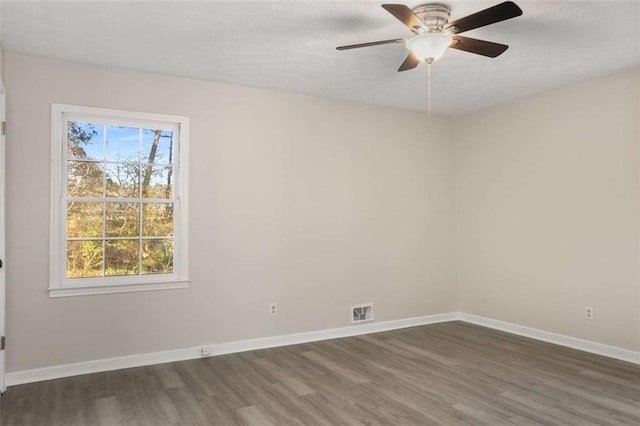 spare room featuring a ceiling fan, wood finished floors, visible vents, and baseboards