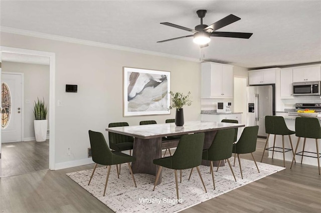 dining area with crown molding, light wood-style flooring, baseboards, and ceiling fan