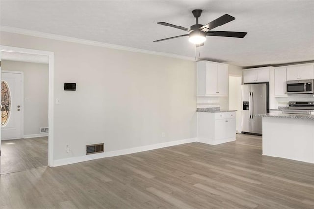 kitchen with stainless steel appliances, visible vents, light wood-style flooring, ornamental molding, and white cabinetry