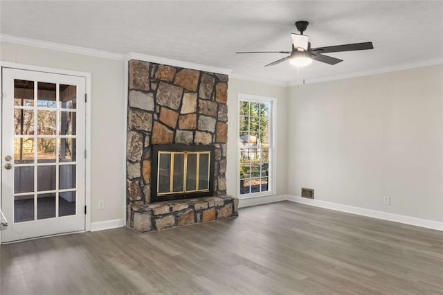 unfurnished living room featuring a fireplace, wood finished floors, visible vents, baseboards, and ornamental molding