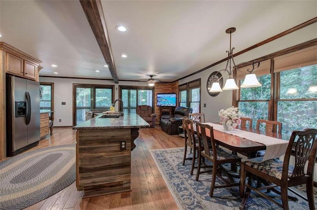 dining room with beamed ceiling, sink, crown molding, light wood-type flooring, and ceiling fan