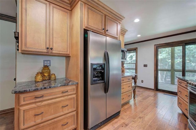 kitchen with crown molding, stainless steel appliances, light wood-type flooring, and dark stone countertops