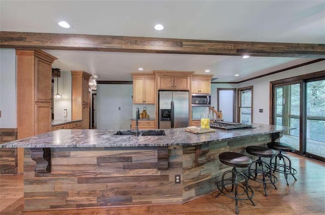 kitchen with sink, appliances with stainless steel finishes, light wood-type flooring, and dark stone countertops