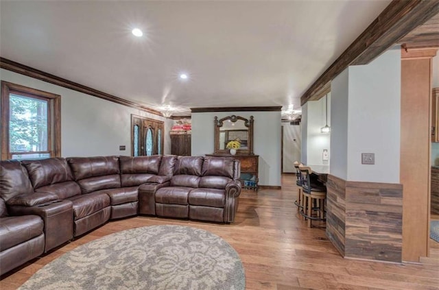 living room featuring light hardwood / wood-style floors, crown molding, and ornate columns