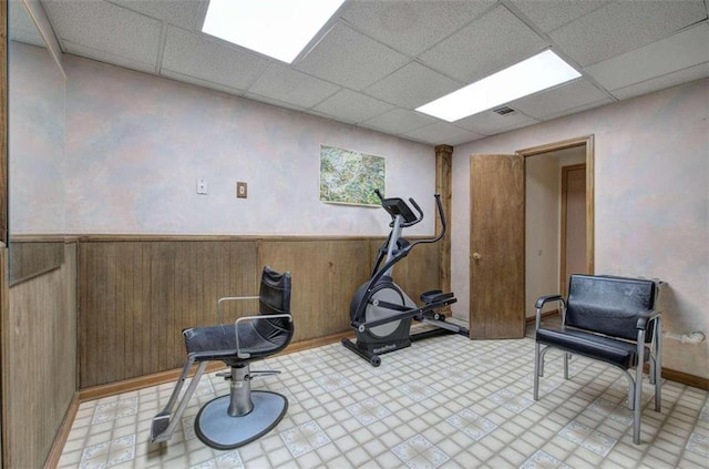 exercise area with a drop ceiling and wooden walls